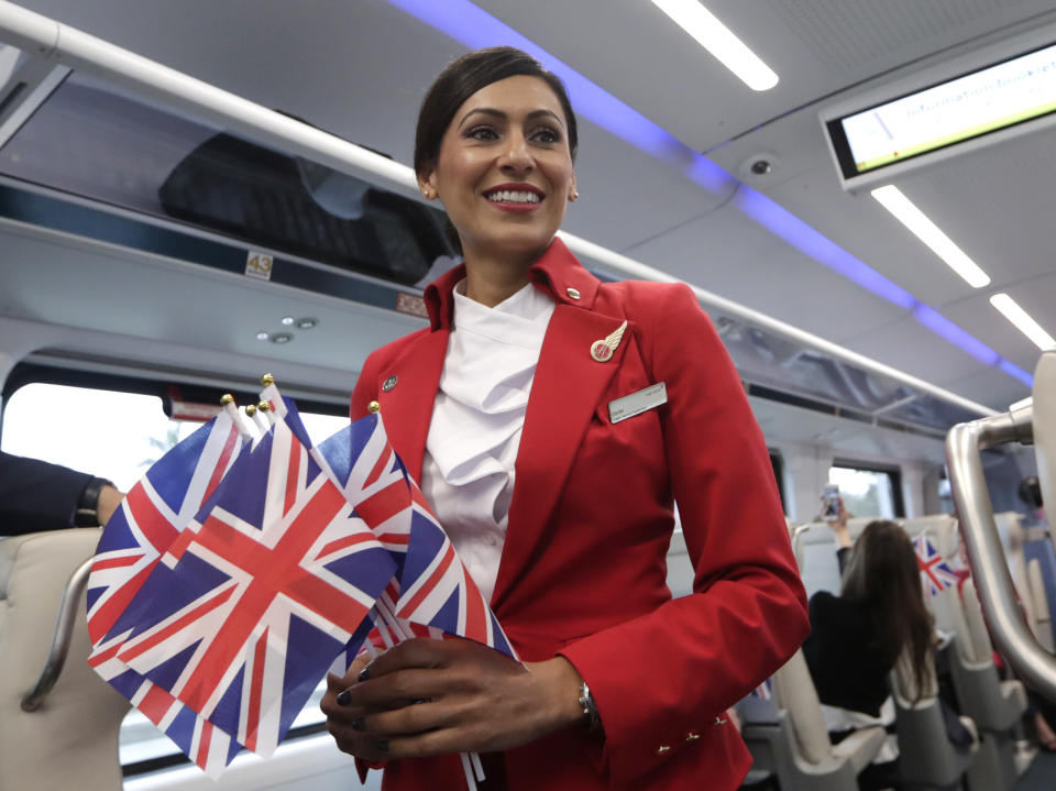 Ombi Farr passes out British flags while riding a Brightline train from Miami to West Palm Beach, Fla. Thursday, April 4, 2019. The state's Brightline passenger trains are being renamed Virgin Trains USA after Richard Branson invested in the new fast-rail project that is scheduled to connect Miami with Orlando. (AP Photo/Lynne Sladky)