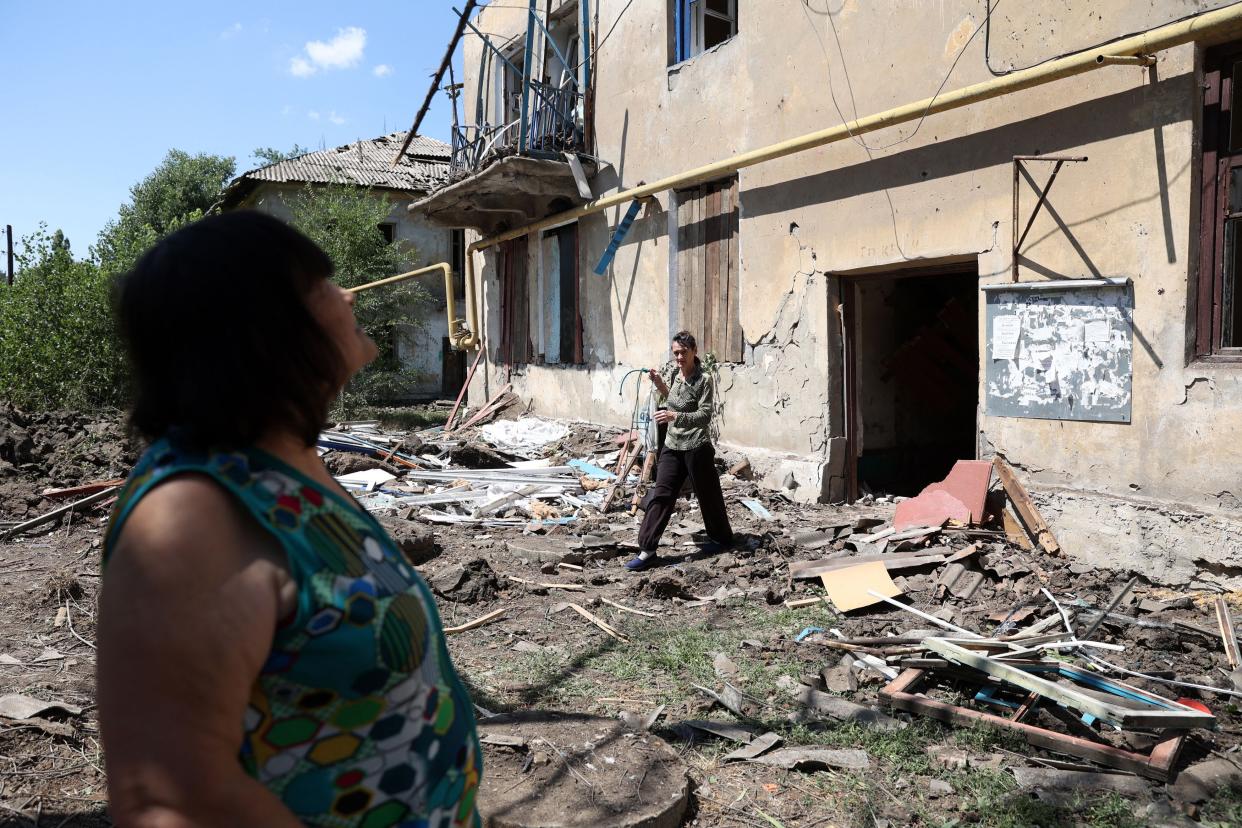 People walk past their partially destroyed building following a Russian airstrike in the town of Toretske, in the Donetsk region, on July 17, 2022, amid the Russian military invasion of Ukraine.