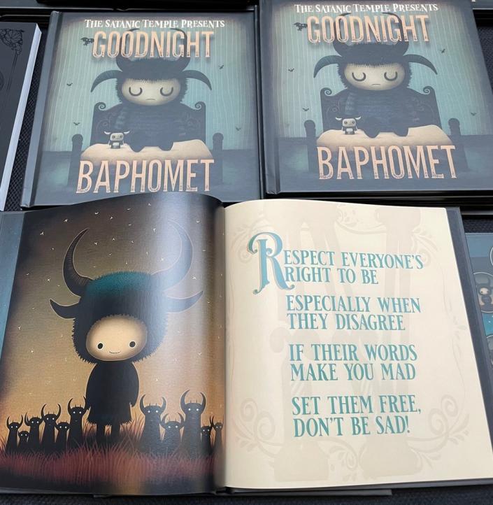 The front cover of the children&#39;s book &#39;Goodnight Baphomet&#39; from The Satanic Temple shows a sleepy child baphomet - a little goat figure with horns, closing its eyes on a bed, a small toy nearby. An inside page has the rhyme: &quot;Respect everyone&#39;s right to be, especially when they disagree. If their words make you mad, set them free - don&#39;t be sad!&quot;
