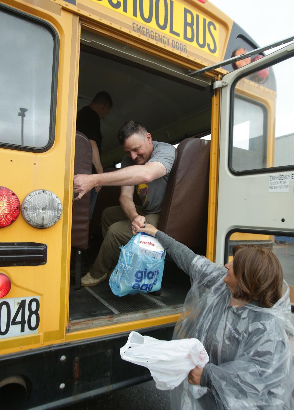 Brian O'Donnell, a volunteer with FirstEnergy, hands food out to Lisa Frank, a volunteer from Surgere, out the back of a Marlington Local bus at the Akron-Canton Regional Foodbank's Stark County Campus in Canton.