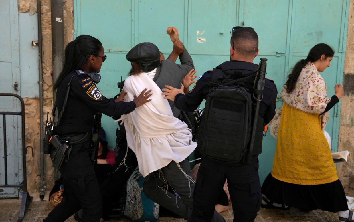 Israeli police grasp a Jewish worshipper and lead him away from Temple Mount