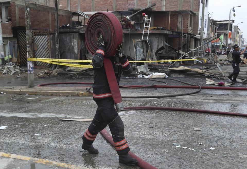 Un bombero se traslada a otro lugar después de rociar agua en una casa cercana adonde explotó un camión de gas en el barrio de Villa María de Lima, Perú, el jueves 23 de enero de 2020. Un camión cisterna de gas natural explotó en esta área urbana del sur de Lima dejando dos muertos, unas 50 personas heridas y al menos una docena de casas quemadas. (AP Foto / Martín Mejía)