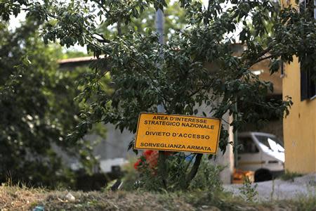 A sign which reads, "Prohibited to enter. Under close weapon surveillance" at an orchard confiscated from the Camorra clan, or the local mafia, in Chiaiano next to Scampia, district of northern Naples, August 21, 2013. The orchard is part of a nationwide campaign to use confiscated gang assets to persuade youths from sink estates like Scampia that there is an alternative to drugs and working for the mob. Picture taken August 21, 2013. REUTERS/Alessandro Bianchi