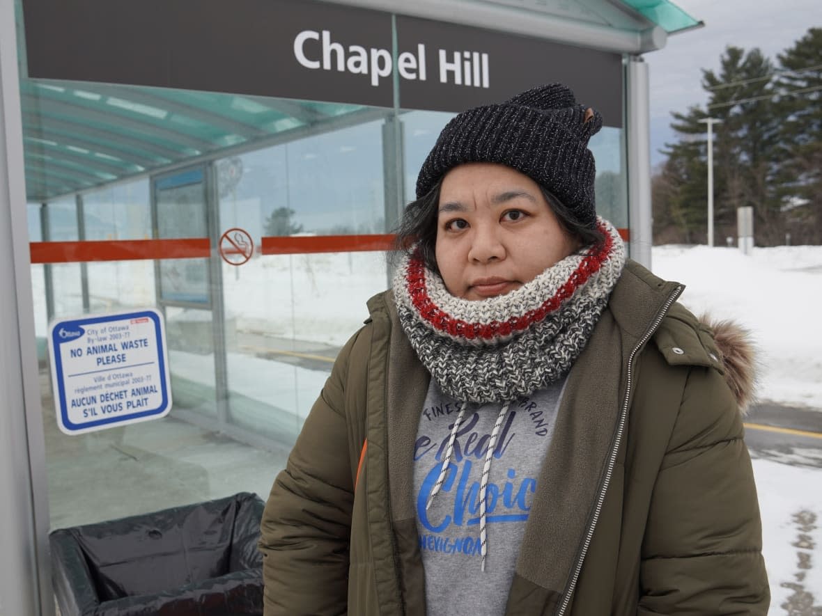 Natalie Chan stands at the Chapel Hill South park-and-ride on Tuesday afternoon. She walked 15 minutes to get there, eventually catching two buses and walking farther to get to the nearest grocery store, which is only a few kilometres away. (Georges-Etienne Nadon-Tessier/CBC - image credit)