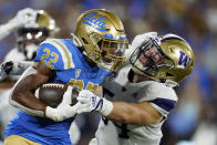 UCLA's Keegan Jones (22) stiff-arms Washington's Drew Fowler on a kick return during the first half of an NCAA college football game Friday, Sept. 30, 2022, in Pasadena, Calif. (AP Photo/Marcio Jose Sanchez)