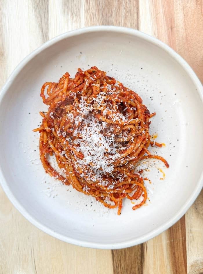 Plate of spaghetti with tomato sauce and a sprinkle of grated cheese, viewed from above