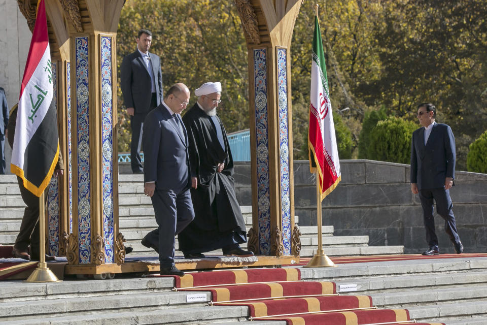 In this photo released by official website of the Office of the Iranian Presidency, Iraqi President Barham Salih, left, and his Iranian counterpart Hassan Rouhani walk down the steps during an official welcome ceremony for Salih at the Saadabad Palace in Tehran, Iran, Saturday, Nov. 17, 2018. Salih is visiting Iran less than two weeks after the United States restored oil sanctions that had been lifted under the 2015 nuclear deal. (Iranian Presidency Office via AP)