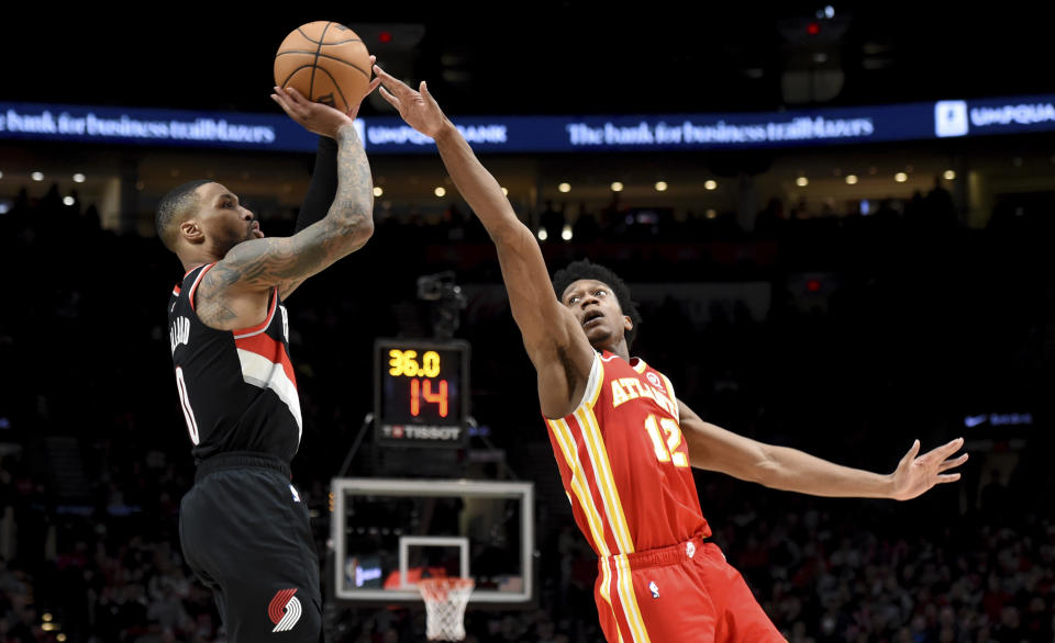 Portland Trail Blazers guard Damian Lillard, left, hits a shot over Atlanta Hawks forward De'Andre Hunter, right, during the second half of an NBA basketball game in Portland, Ore., Monday, Jan. 30, 2023. The Blazers won 129-125. (AP Photo/Steve Dykes)