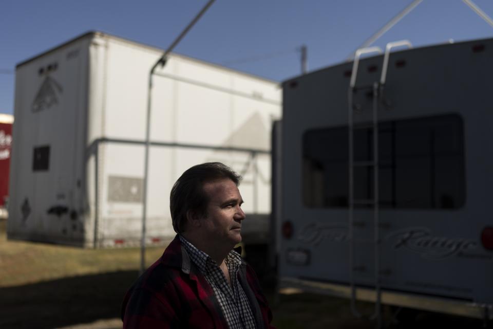 Ron Caetano stands for a photo next to a trailer packed with his family's belongings in the Island District of Lemoore, Calif., Wednesday, April 19, 2023. Caetano packed photos and valuables in a trailer and food in carry totes so he can leave home in less than an hour should the river water rush in. He moved rabbits and chickens and their automatic feeders to higher ground. Many of his shelves are bare, and his family and dogs are ready to go. (AP Photo/Jae C. Hong)