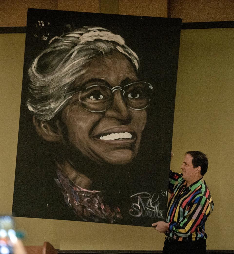Artist Rob Surette presents a painting of Rosa Parks during the Greater Framingham Community Church's 37th annual Dr. Martin Luther King Jr. Day Celebration at the Verve Hotel Tapestry in Natick, Jan. 15, 2024.