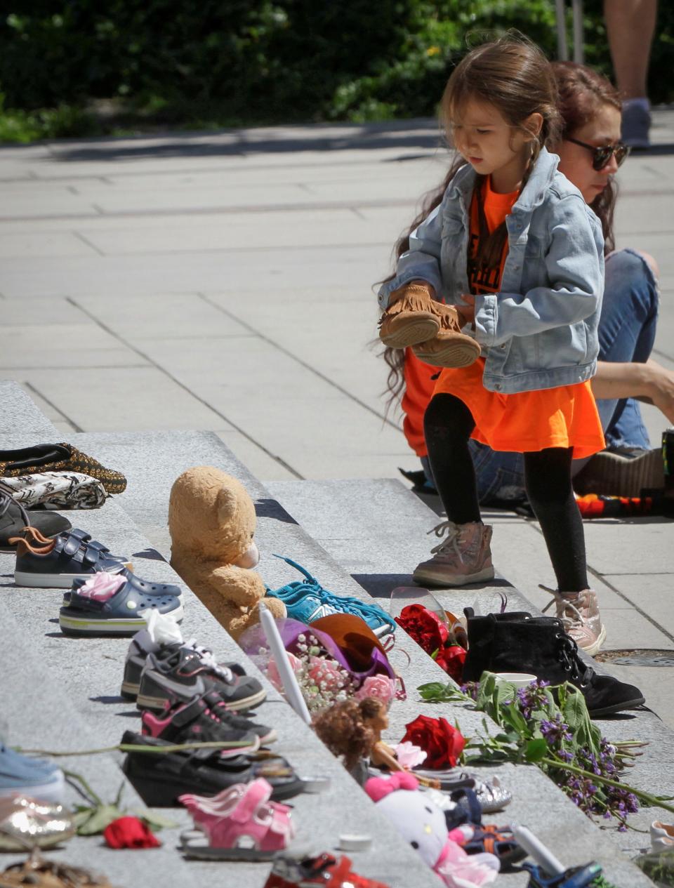 <p>A girl tries to put a pair of shoes on the staircase while attending a memorial event for the 215 children whose remains have been found buried at a former Kamloops residential school outside Vancouver Art Gallery in Vancouver, British Columbia, Canada, May 29, 2021 .The reported discovery of the remains of 215 indigenous children at a former residential school in Kamloops in western Canada has shocked Canadian people.In a press release on Friday, the British Columbia Assembly of First Nations said it is grieving the location of the 215 children. (Photo by Liang Sen/Xinhua via Getty Images)</p> 