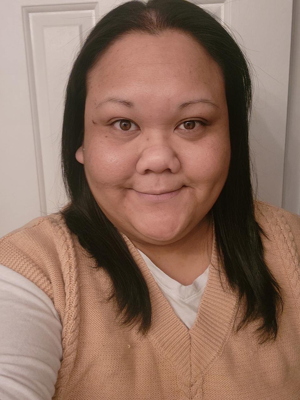 Brunette woman smiling with a brown sweater