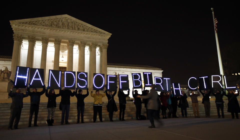 A group of people organized by the NYC Light Brigade and the women's rights group UltraViolet, use letters in lights to spell out their opinion, in front of the Supreme Court, Monday, March 24, 2014, in Washington. Holding the "H" in "Hands" is Rep. Keith Ellison, D-Minn. The Supreme Court is weighing whether corporations have religious rights that exempt them from part of the new health care law that requires coverage of birth control for employees at no extra charge. (AP Photo/Alex Brandon)