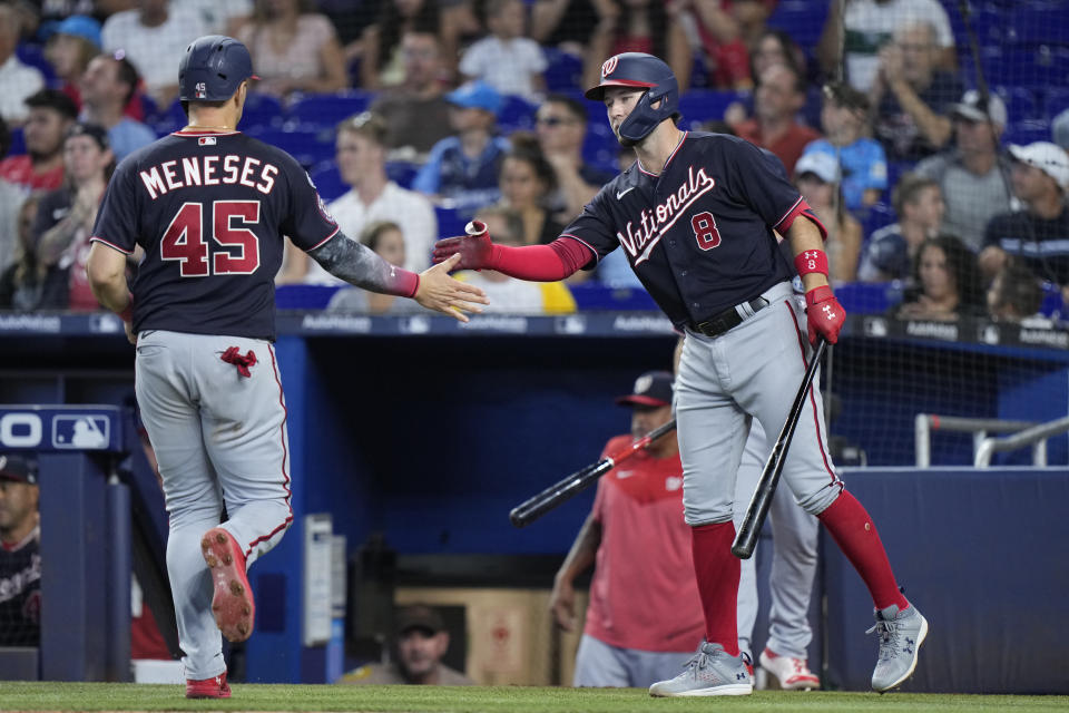 Washington Nationals' Carter Kieboom (8) congratulates Joey Meneses (45) after Meneses scored on a throwing error by Miami Marlins shortstop Joey Wendle during the fourth inning of a baseball game, Saturday, Aug. 26, 2023, in Miami. (AP Photo/Wilfredo Lee)