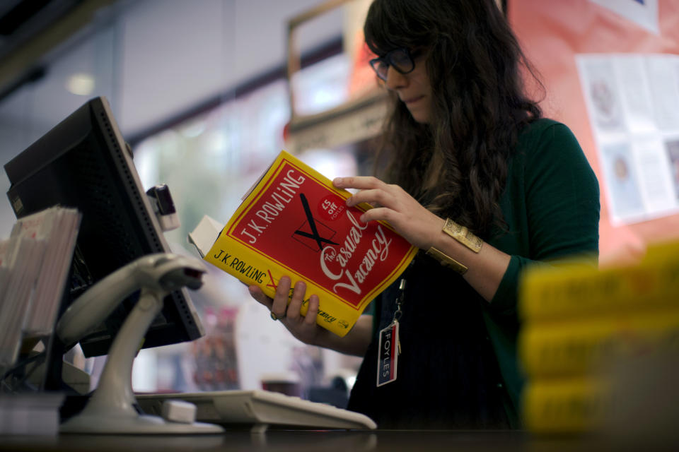 An employee looks at a copy of the "The Casual Vacancy" by author J.K. Rowling at a book store in London, Thursday, Sept. 27, 2012. British bookshops are opening their doors early as Harry Potter author J.K. Rowling launches her long anticipated first book for adults. Publishers have tried to keep details of the book under wraps ahead of its launch Thursday, but "The Casual Vacancy" has gotten early buzz about references to sex and drugs that might be a tad mature for the youngest "Potter" fans. (AP Photo/Matt Dunham)