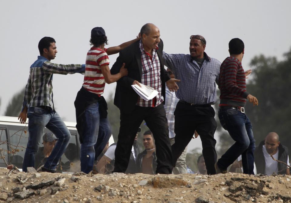 Supporters of the Muslim Brotherhood and ousted Egyptian President Mohamed Mursi push at a journalist (C), who they claim is a pro-army, as they attempt to get him to leave the area outside the police academy, where Mursi's trial took place, on the outskirts of Cairo, November 4, 2013. Mursi struck a defiant tone on the first day of his trial on Monday, chanting 'Down with military rule', and calling himself the country's only 'legitimate' president. Mursi, an Islamist who was toppled by the army in July after mass protests against him, appeared angry and interrupted the session repeatedly, prompting a judge to adjourn the case. REUTERS/Amr Abdallah Dalsh (EGYPT - Tags: POLITICS CIVIL UNREST)