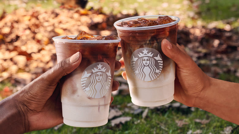 Holding two apple crisp macchiatos 