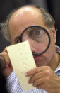 FILE - In this Nov. 24, 2000, file photo, Broward County, Fla., canvassing board member Judge Robert Rosenberg uses a magnifying glass to examine a disputed election ballot at the Broward County Courthouse in Fort Lauderdale, Fla. Florida will never experience another election meltdown exactly like the one that made the state an international laughingstock in 2000, when after a five-week recount and court battle George W. Bush edged Al Gore and won the presidency. State leaders eliminated computer punchcard ballots, implemented statewide recount laws and made it easy to cast and process ballots before Election Day.(AP Photo/Alan Diaz, File)