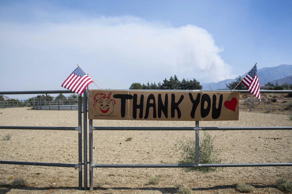 A thank you sign hangs in Juniper Hills, Calif on Monday, Sept. 21, 2020 after the Bobcat fire burned through the area as the smoke is seen from fires in Paradise Springs. (Sarah Reingewirtz/The Orange County Register via AP)