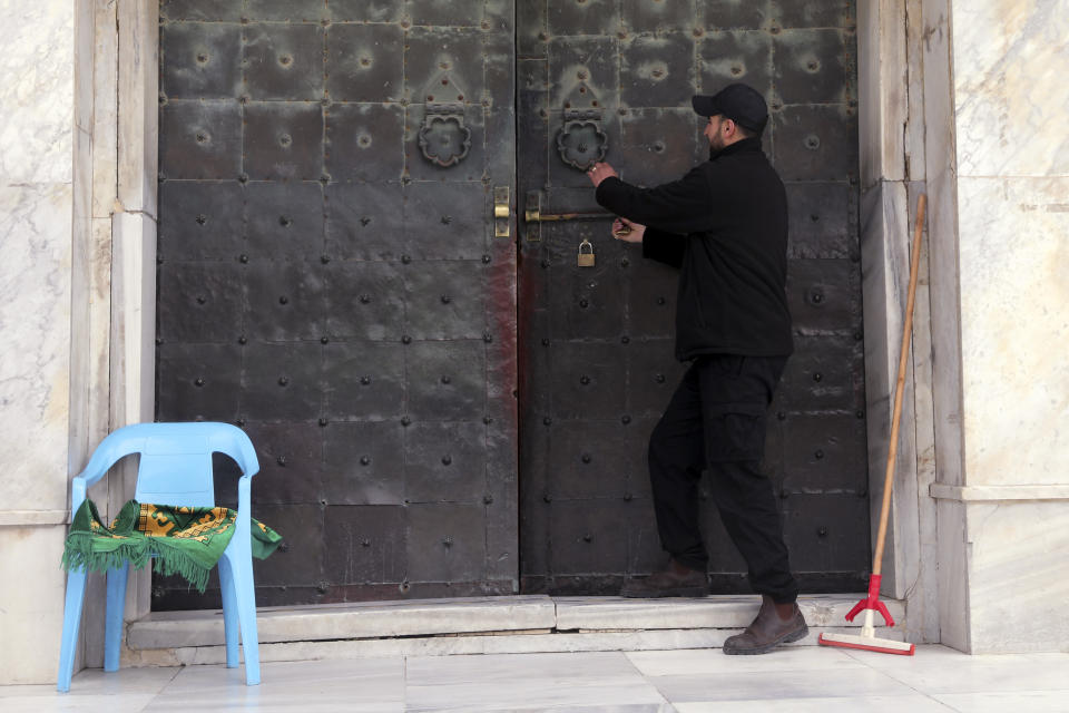 A guard shuts thne dorr at Al-Aqsa mosque in Jerusalem, Sunday, March 15, 2020. Israel imposed sweeping travel and quarantine measures more than a week ago but has seen its number of confirmed coronavirus cases double in recent days, to around 200. On Saturday, the government said restaurants, malls, cinemas, gyms and daycare centers would close. (AP Photo/Mahmoud Illean)
