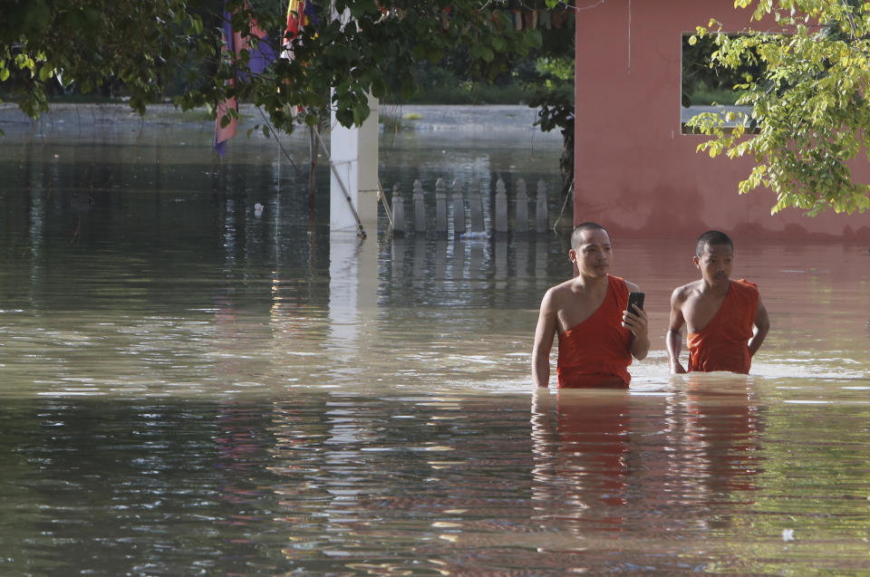 Buddhist monks walk through a flooded pagoda following recent rains on the outskirts of Phnom Penh, Cambodia, Wednesday, Oct. 14, 2020. A Cambodian disaster official said Wednesday that more than 10,000 people have been evacuated to safety places after a tropical storm hit the country, causing the flash flood. (AP Photo/Heng Sinith)