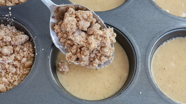 spooning crumble into muffin tin