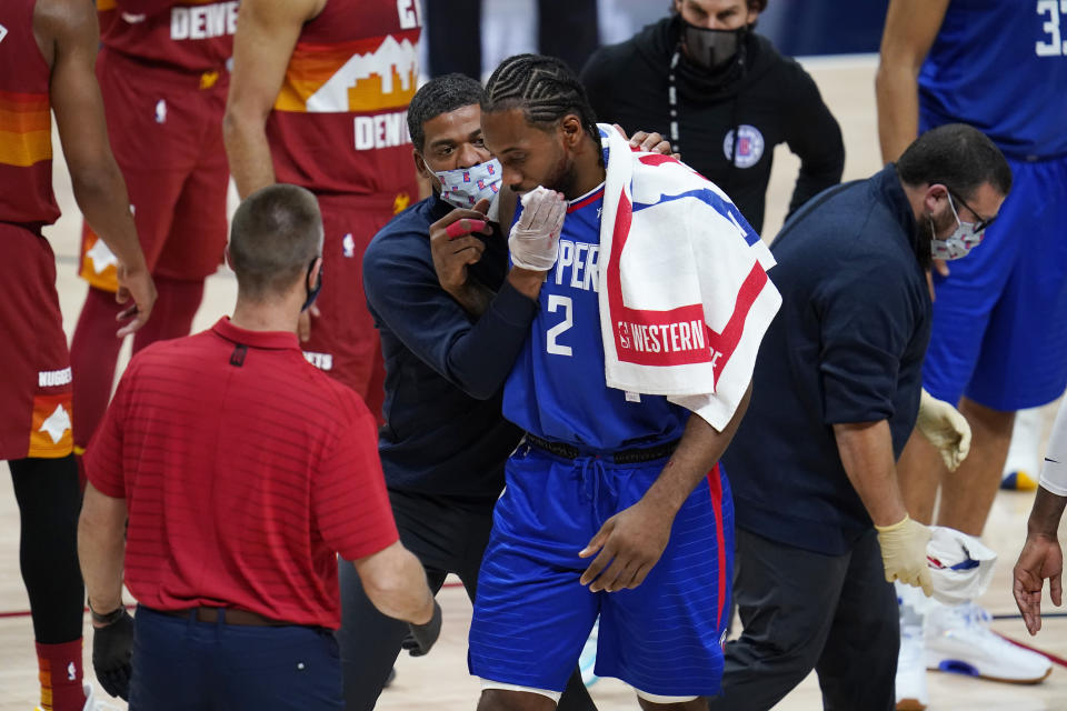 Los Angeles Clippers forward Kawhi Leonard is helped off the court after suffering an injury during the second half of the team's NBA basketball game against the Denver Nuggets on Friday, Dec. 25, 2020, in Denver. (AP Photo/David Zalubowski)