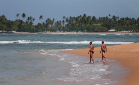 Tourists get into the water at Unawatuna beach in Galle