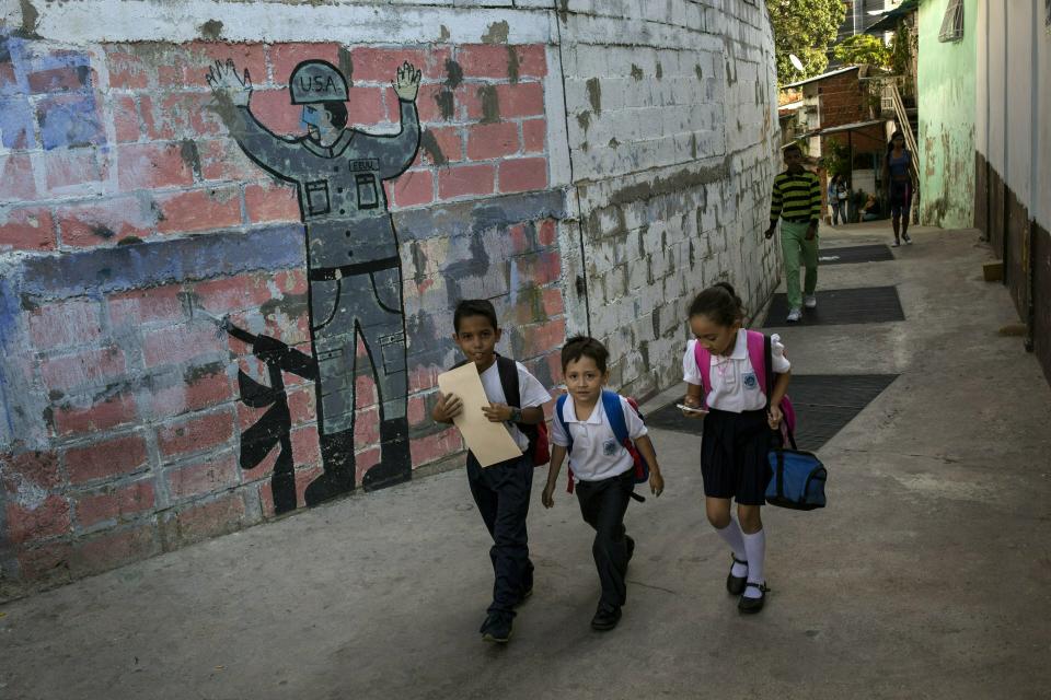 In this Feb. 1, 2019 photo, children walk past a mural that depicts the surrender of a U.S. soldier, in Caracas, Venezuela. Caritas, a charity run by the Roman Catholic church, estimates that child malnutrition more than doubled last year in Venezuela due to widespread food shortages and 7-digit hyperinflation, while 48 percent of pregnant women in low-income neighborhoods are also underfed. (AP Photo/Rodrigo Abd)