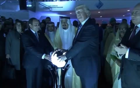 President Donald Trump places his hands on a glowing orb as he tours with other leaders the Global Center for Combating Extremist Ideology in Riyadh - Credit: Reuters