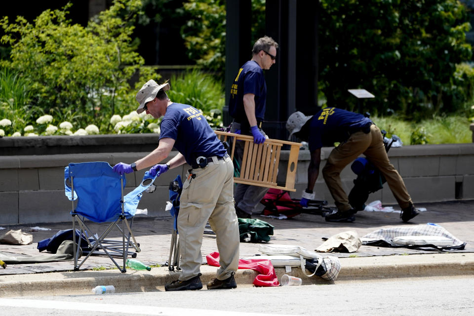 Agentes del FBI recolectan evidencia mientras retiran pertenencias abandonadas un día después de un tiroteo en Highland Park, Illinois, el martes 5 de julio de 2022. (AP Foto/Charles Rex Arbogast)