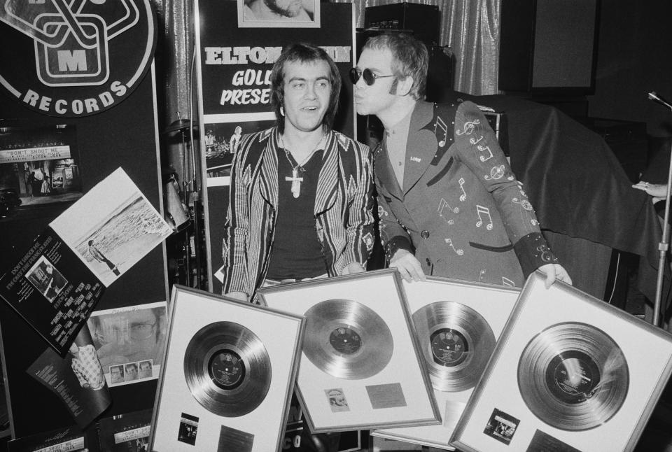 Bernie Taupin and Elton John at a 1973 ceremony to award them gold discs for four of their co-written albums. (Photo: Michael Putland/Getty Images)