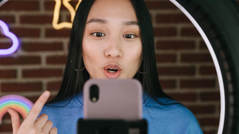 Eine junge Frau nimmt Social-Media-Inhalte für TikTok oder Instagram auf ihrem Smartphone auf