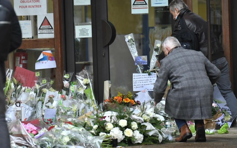 People lay flowers at the middle school in Conflans-Sainte-Honorine - BERTRAND GUAY/AFP via Getty Images