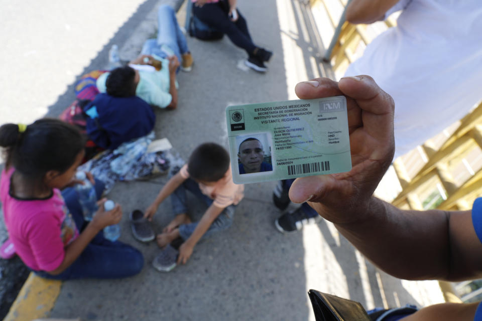 Honduran migrant Jose Maria Dubon Gutierrez shows his legal permission to stay in Mexico's southern states as he waits with his family, behind, at a border crossing between Guatemala and Mexico for his family's turn to show Mexican immigration officers their documents near Ciudad Hidalgo, Mexico, Thursday, June 6, 2019. While Mexico has been discouraging the kind of large-scale caravans that it saw in 2018 and the first few months of 2019, Trump's administration wants Mexico to do more to curb migrants from reaching the U.S. border. (AP Photo/Marco Ugarte)