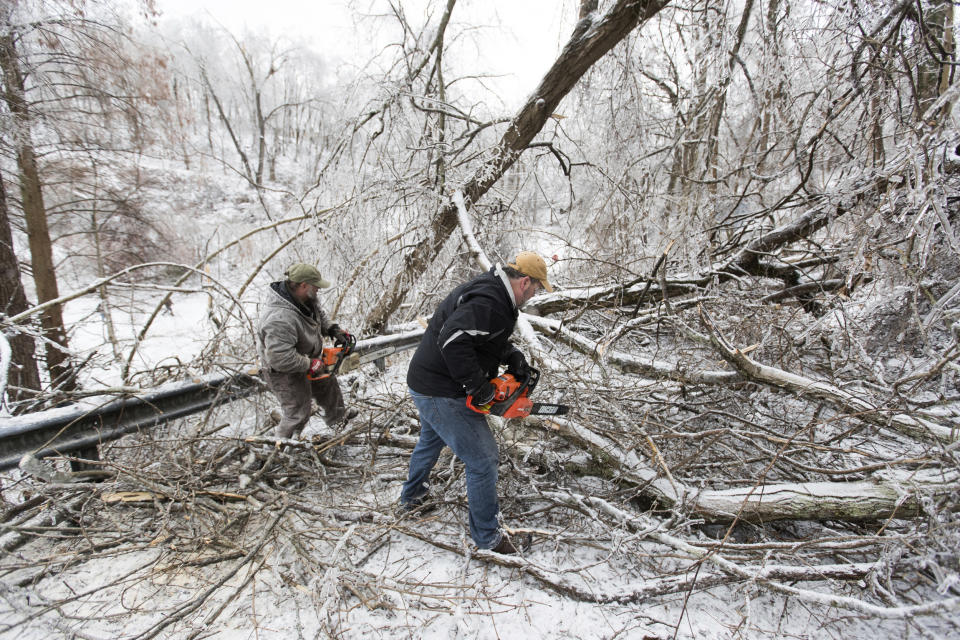 Area residents work to clear downed trees along Honeysuckle Lane on Feb. 16, 2021, in Huntington, W.Va., (Sholten Singer / The Herald-Dispatch via AP file)
