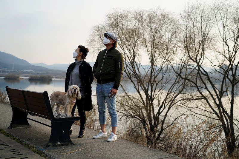 A couple wearing masks to prevent contracting the coronavirus spend their time at a Han River park in Namyangju