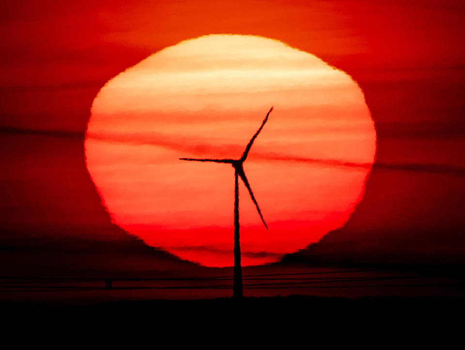 The sun rises behind a wind turbine in Frankfurt, Germany, early Tuesday, Sept. 15, 2020. (AP Photo/Michael Probst)