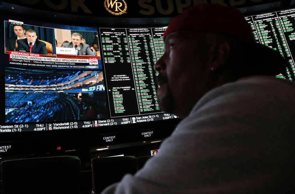 Martinel Johnson watches sports as the first public impeachment hearing of President Donald Trump plays on a screen at the Superbook sports book inside the Westgate casino-hotel Wednesday, Nov. 13, 2019, in Las Vegas. (AP Photo/John Locher)