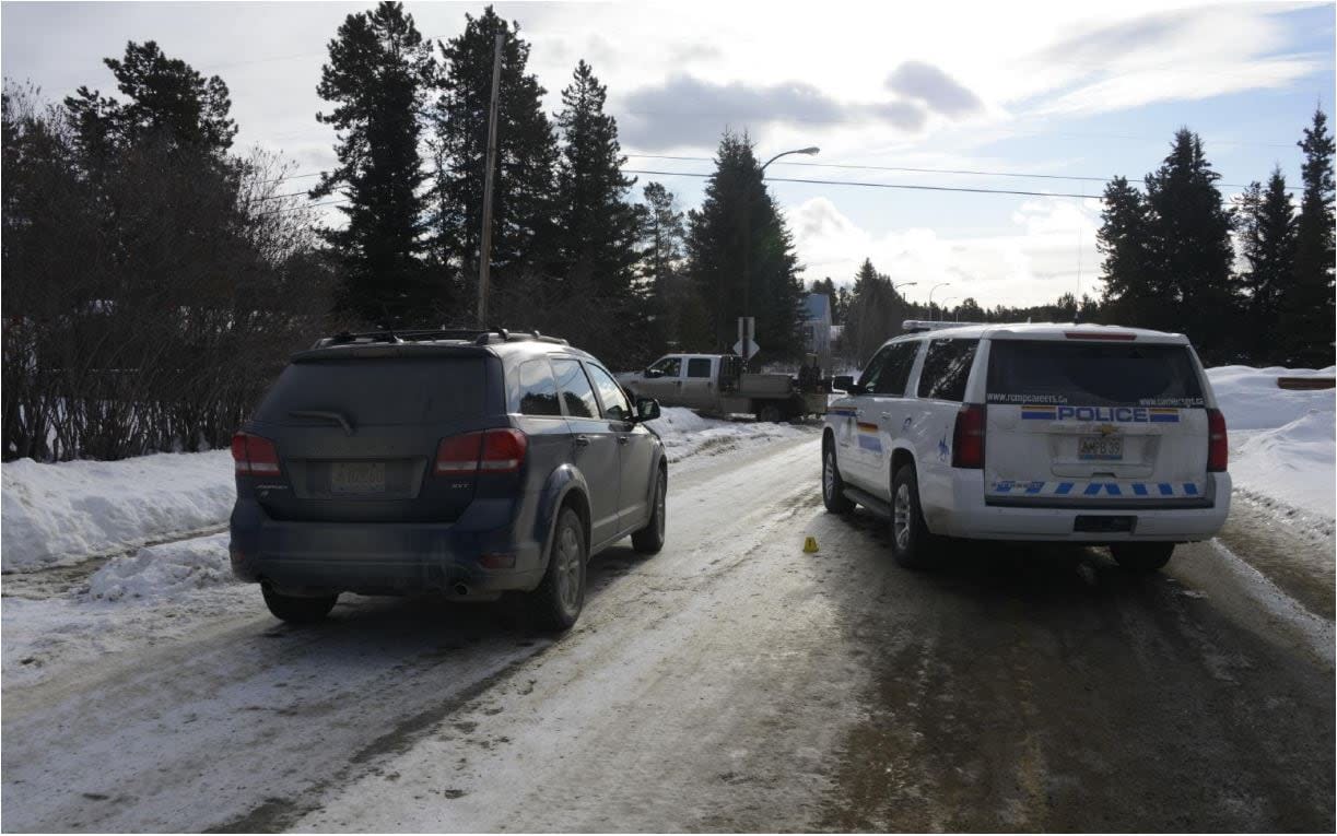 Two RCMP vehicles, including an unmarked SUV on the left, sit on a street in Whitehorse's Porter Creek neighbourhood in March 2020. Officers were responding to a call about a man who showed up to his ex-father-in-law's house with a rifle. The man's truck is in the background. (Alberta Serious Incident Response Team - image credit)