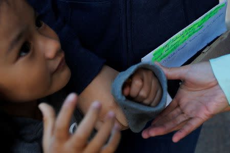 An ethnic Chinese Christian, who fled Indonesia after wide scale rioting and overstayed her visa in the U.S., holds her daughter's hand and a handwritten list of appointments with ICE, the last entry reading "...Instructed to report on 10/9/17 at 9:30 with tickets and itinerary to directly depart the U.S. on or before 11/9/17..,." before a scheduled ICE family meeting including her husband and five year-old daughter in Manchester, New Hampshire, U.S., October 13, 2017. REUTERS/Brian Snyder