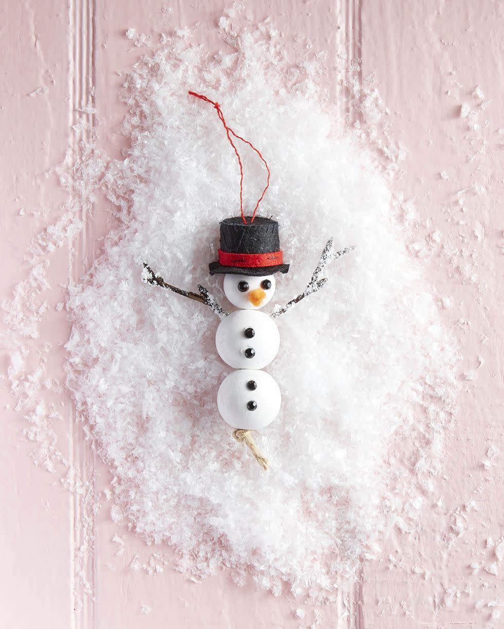 homemade snowman ornament made from white wooden beads with limbs made of twigs