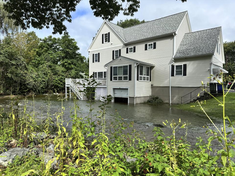 A brook in Leominster, Mass. overflows into the garage of a home following heavy rains overnight, Tuesday, Sept. 12, 2023. (AP Photo/Michael Casey)