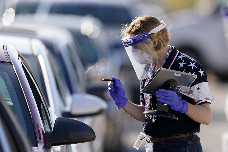 An election worker instructs a voter at a drive-thru polling location Tuesday, Nov. 3, 2020, in Kansas City, Mo. The location was established to provide access for people who have tested positive for COVID-19 and elderly voters. (AP Photo/Charlie Riedel)