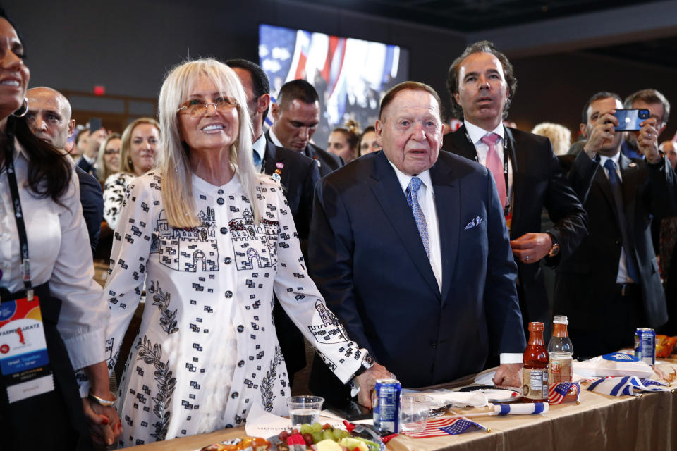 FILE - Las Vegas Sands Corporation Chief Executive and Republican mega donor Sheldon Adelson, center, and his wife, Miriam Adelson, left, listen as President Donald Trump speaks at the Israeli American Council National Summit in Hollywood, Fla., Saturday, Dec. 7, 2019. Miriam Adelson, the controlling shareholder of casino company Las Vegas Sands Corp., plans to sell $2 billion in company stock and buy an unspecified professional sports franchise, the company announced Tuesday, Nov. 28, 2023. Dallas Mavericks owner Mark Cuban is working on a deal to sell a majority stake in the NBA franchise to the Adelson family, a person with knowledge of the talks said late Tuesday. (AP Photo/Patrick Semansky, File)