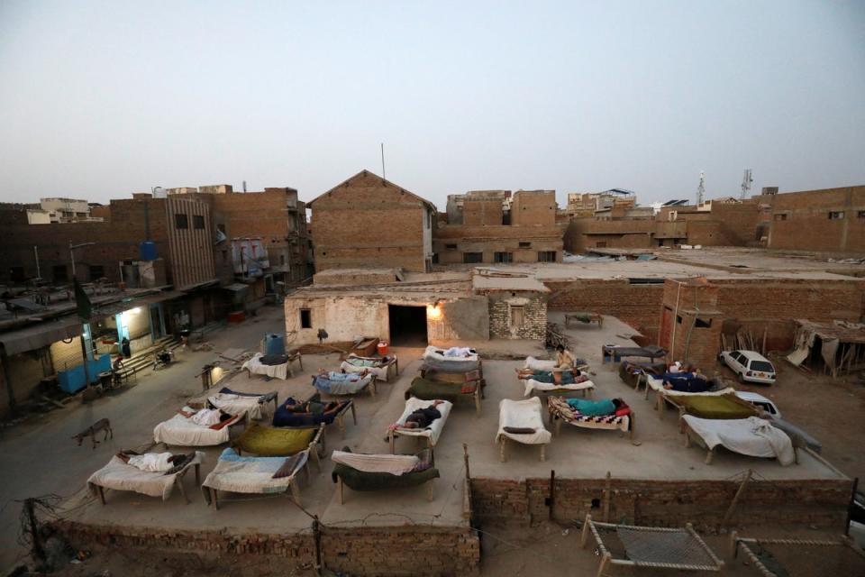 Men sleep on charpoy rope beds on a roof early in the morning during a heatwave (Reuters)