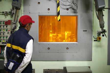 A worker looks through a thick glass window at part of the treatment of nuclear waste at the Areva Nuclear Plant of La Hague, near Cherbourg, western France, in this April 22, 2015 file photo. REUTERS/Benoit Tessier/Files