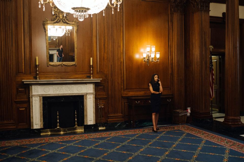 Ocasio-Cortez takes a phone call in the Rayburn Room in the Capitol, where her swearing in ceremony photos were taken in January 2019.