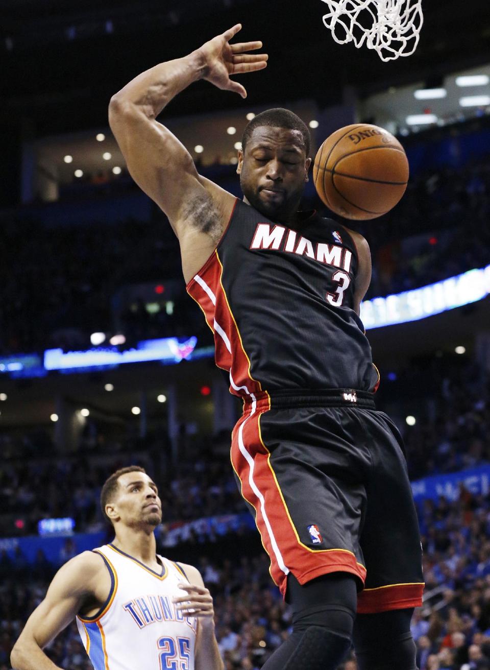 Miami Heat guard Dwyane Wade (3) dunks in front of Oklahoma City Thunder guard Thabo Sefolosha (25) during the first quarter of an NBA basketball game in Oklahoma City, Thursday, Feb. 20, 2014. (AP Photo/Sue Ogrocki)