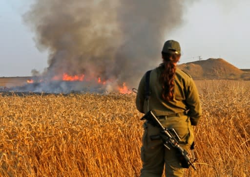 An Israeli soldier looks at a burning wheat field near the Kibbutz of Nahal Oz along the border with the Gaza Strip, on May 15, 2018 after fires were started by Palestinian demonstrators